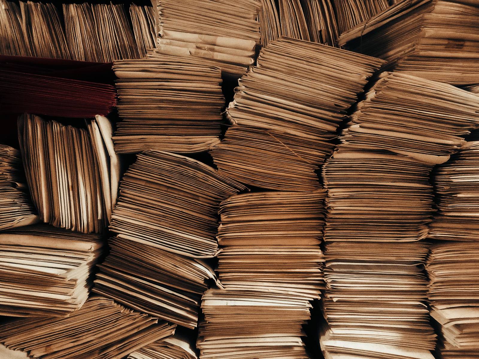 Pilhas de envelopes pardos, todos iguais, empilhados lado a lado até ocupar o quadro inteiro.